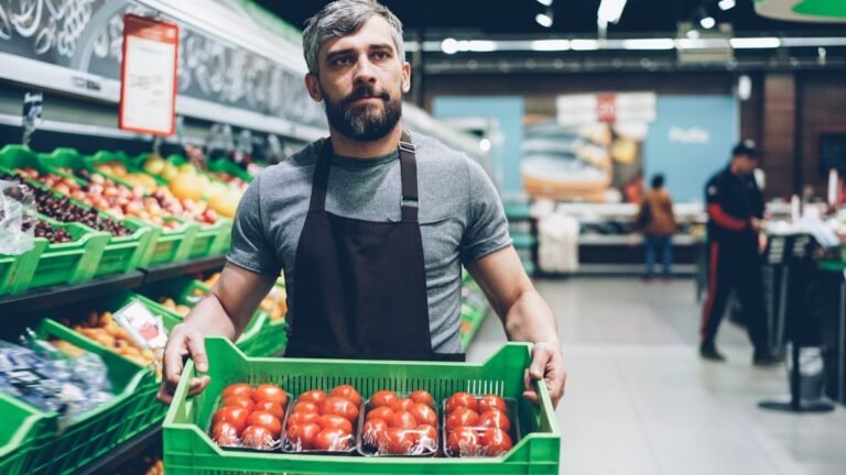 HEB interview questions prep: a grocery worker carrying a crate of tomatoes through the produce aisle