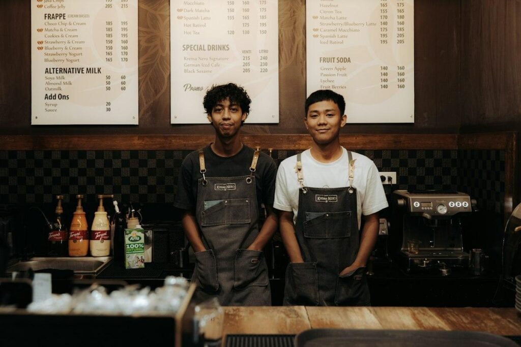 Baristas in aprons behind a coffee shop counter, dressed to match the Starbucks dress code
