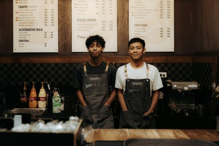 Baristas in aprons behind a coffee shop counter, dressed to match the Starbucks dress code