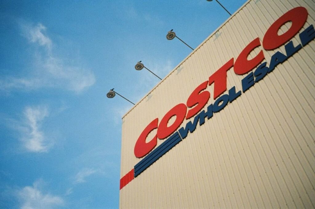 Costco Wholesale sign on a warehouse wall under a blue sky, the employer behind Costco employee benefits
