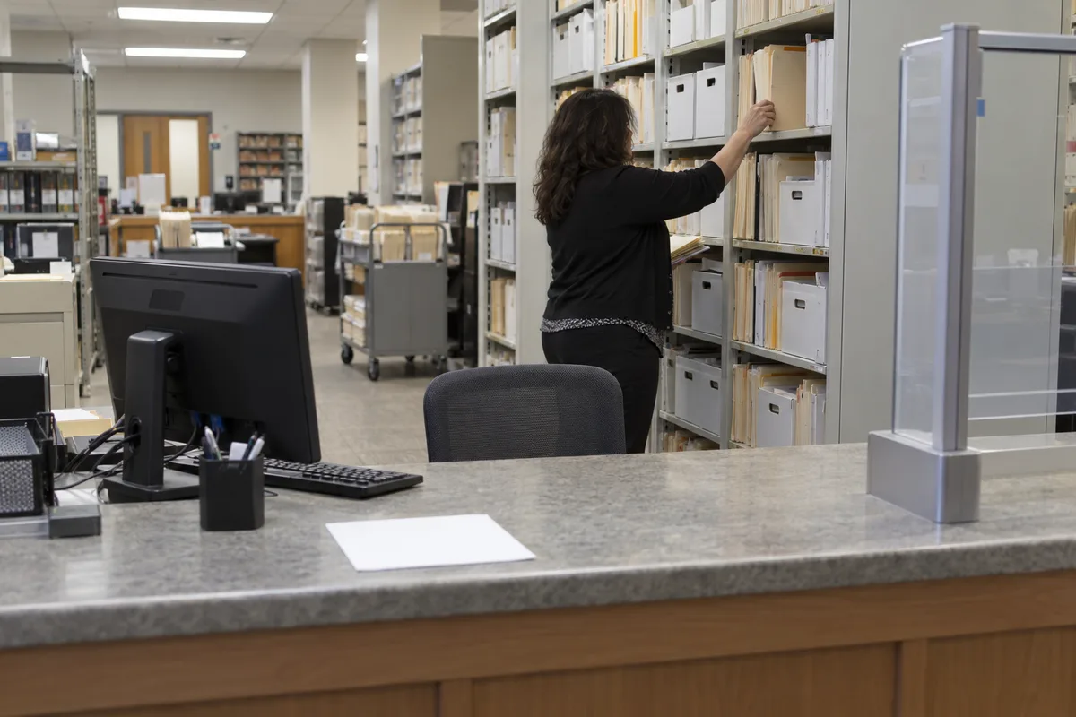 How long does a background check take: a county court clerk pulling a paper record by hand