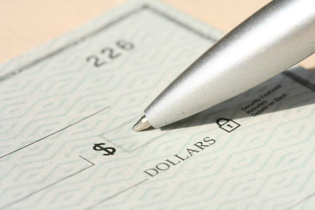 Walmart pay stub and paycheck: pen tip resting on a blank dollars check